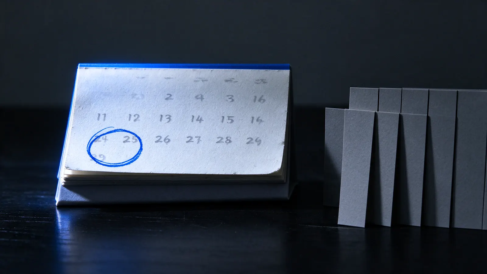 Calendário de mesa com uma data circulada em azul ao lado de fichas, metade afastada