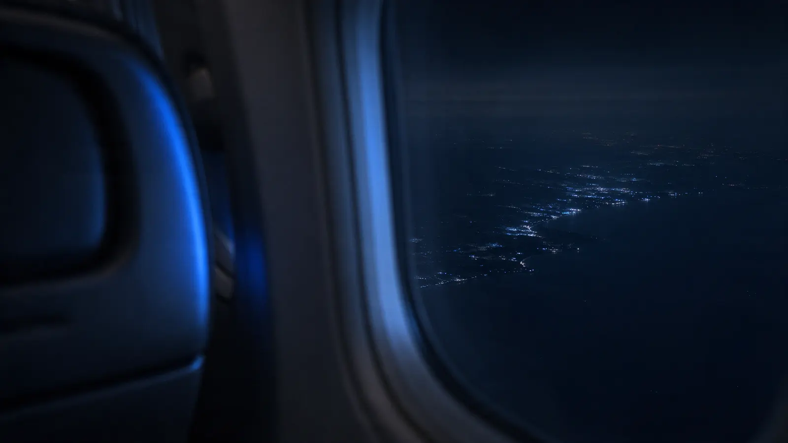 Vista da janela do avião à noite sobre uma costa iluminada