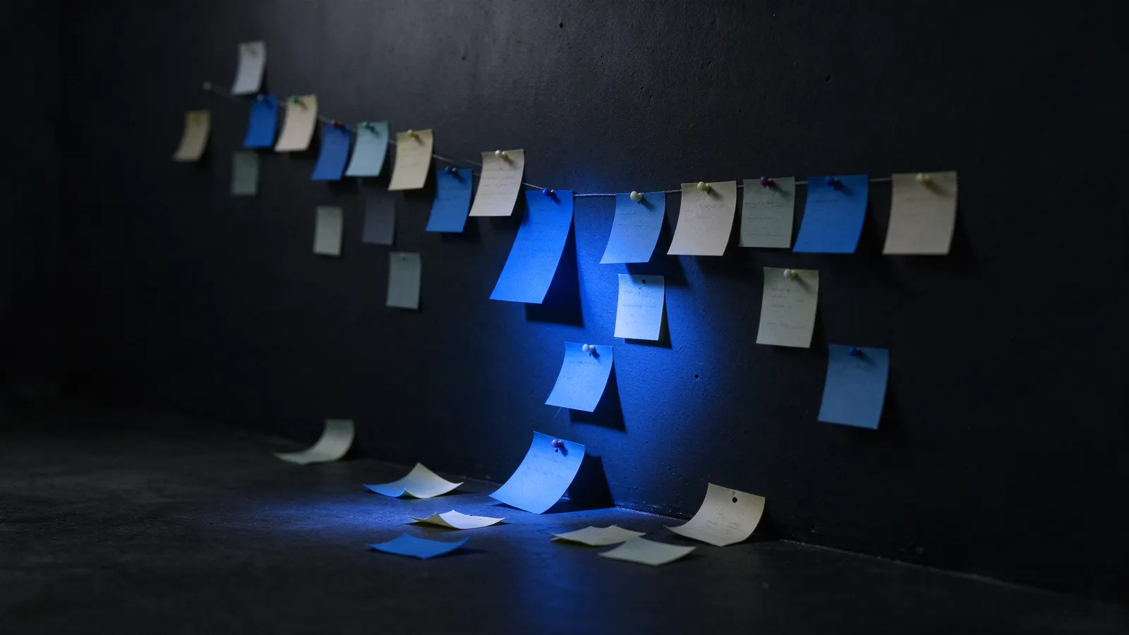 Linha do tempo na parede cheia de post-its, alguns caídos no chão