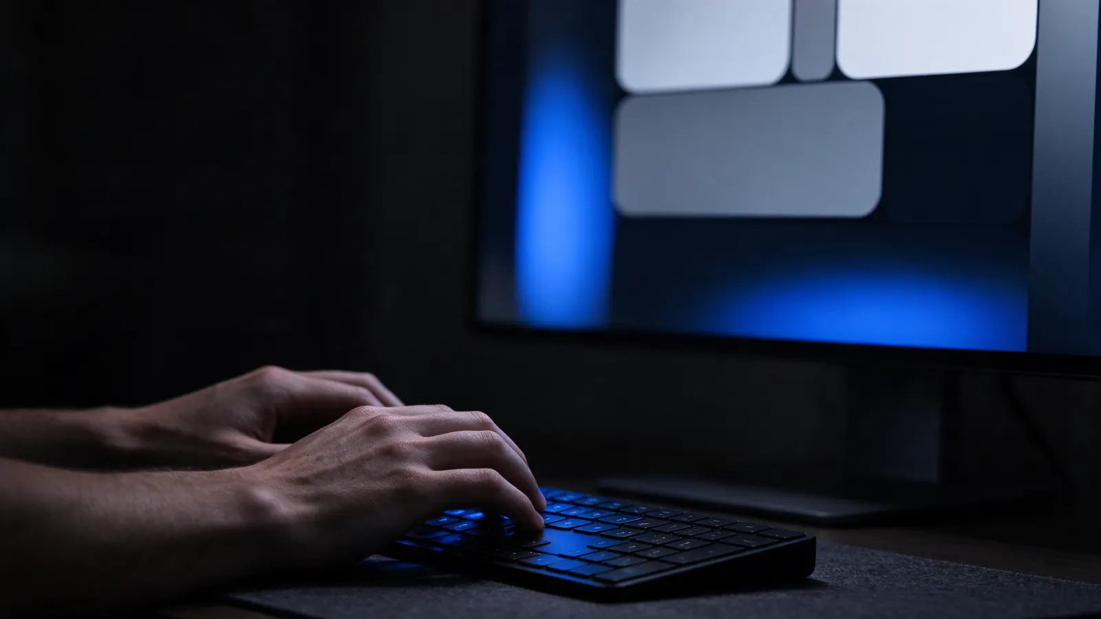 Mãos digitando diante de um monitor com blocos de interface grandes e contrastados